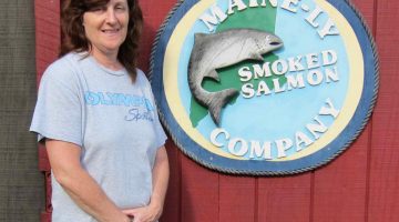 Karen Constant standing next to Mainely Smoked salmon sign