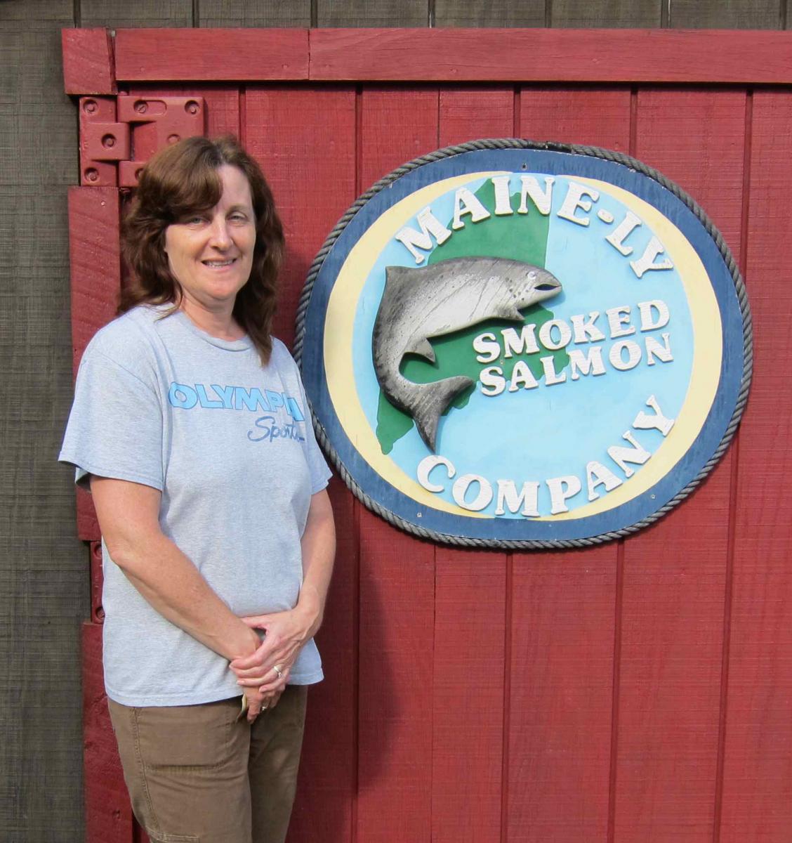 Karen Constant standing next to Mainely Smoked salmon sign