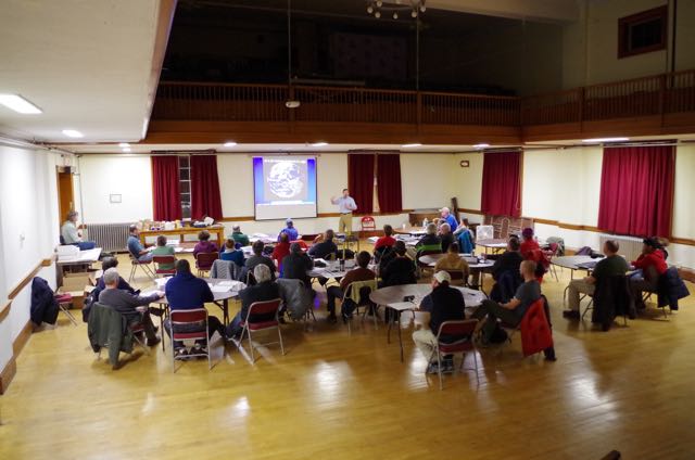 A view from the back of the classroom, a man standing at a projection screen