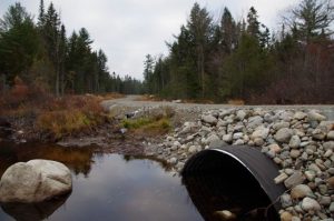 Gravel forest road and arched stream crossing Stream with smart culvert on Penobscot Nation land in Maine