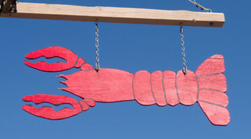 a hand painted lobster sign against the blue sky