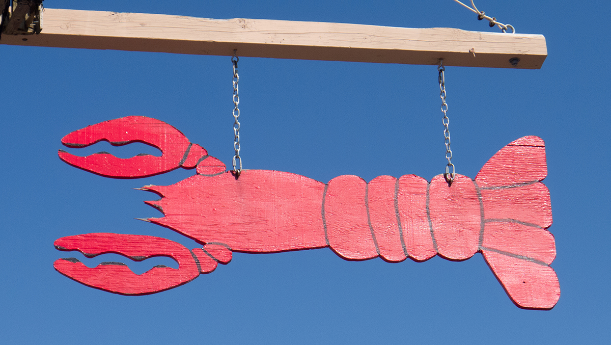 a hand painted lobster sign against the blue sky