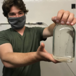 Alex Ascher holding a jar of lobster larvae