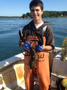 a person in a boat wearing chest waders holding a lobster