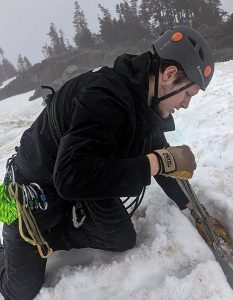 a person wearing a helmet kneeling to dig in the ice