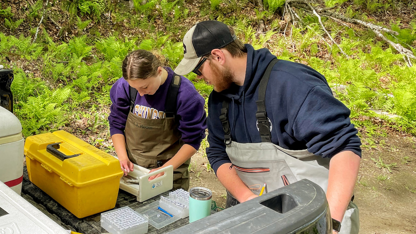 two people looking over equipment in the back of a pickup truck