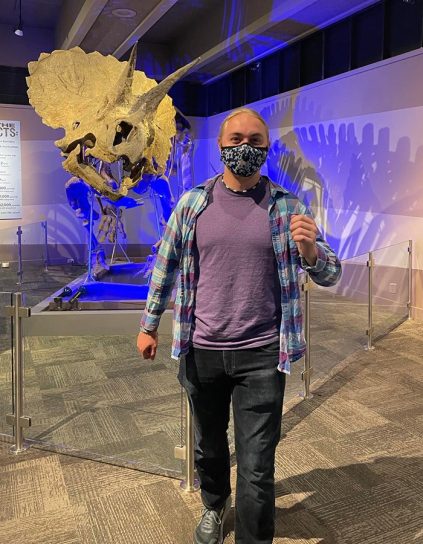 Evan Busch in front of a dinosaur skeleton