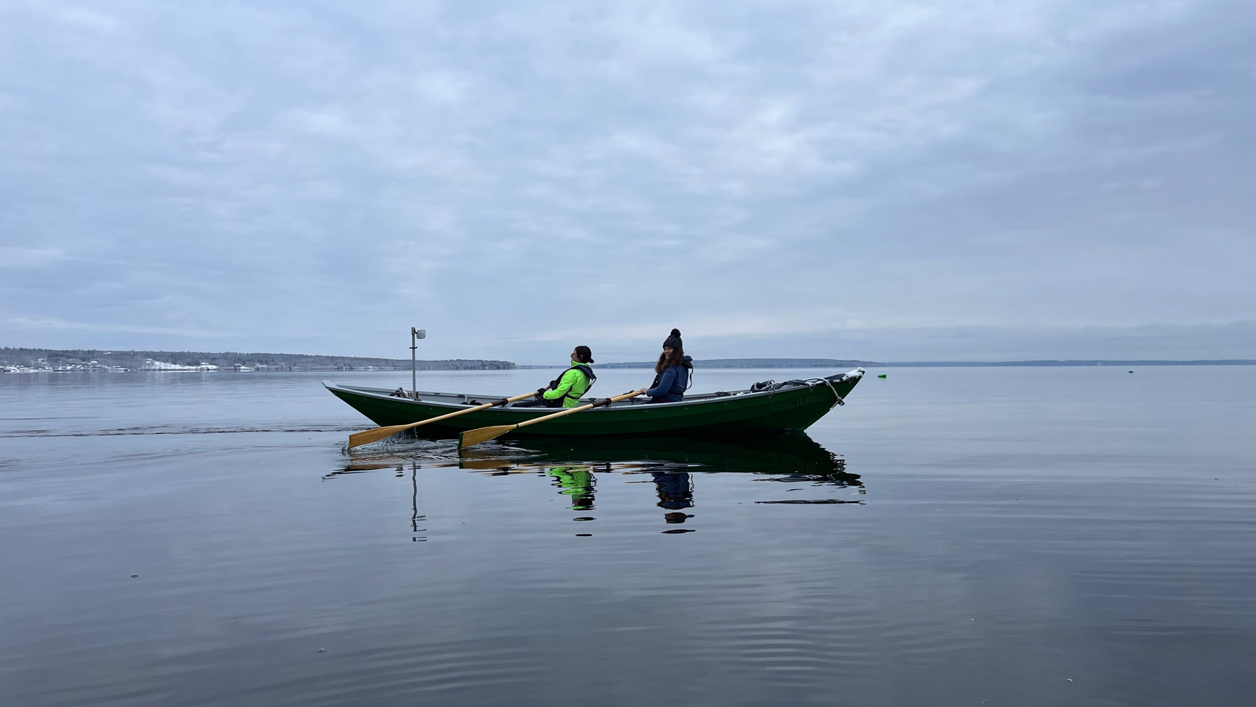 two people rowing a boat under overcast sky