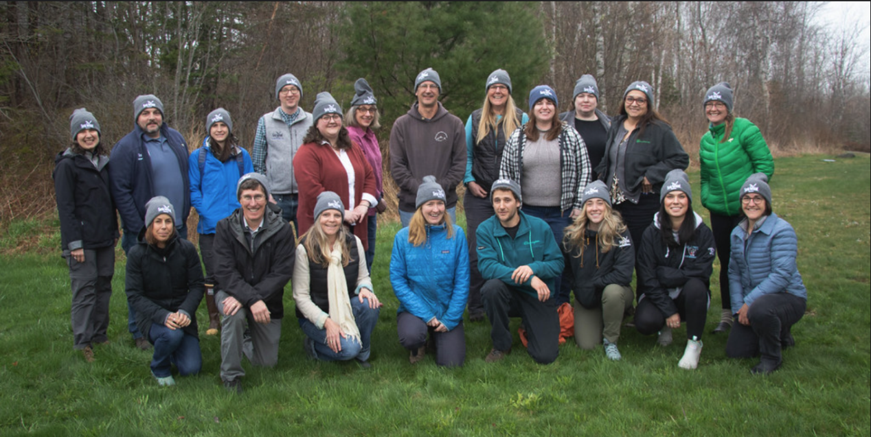 group photo of 20 people wearing Maine Sea Grant hats in front of trees
