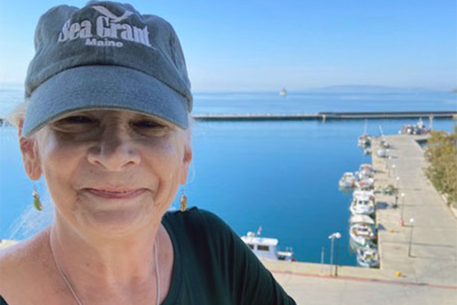 person in a Sea Grant hat with a coastal background