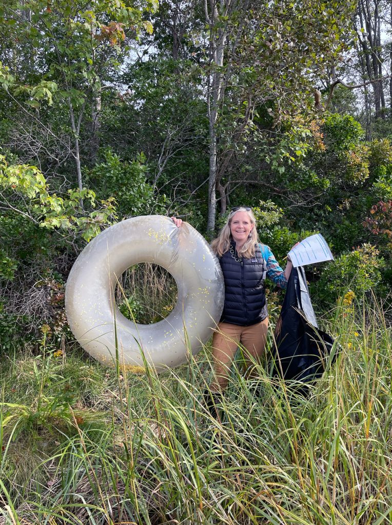 Beth Bisson smiles for the camera carrying a round swimming tube found while cleaning up some marine debris.