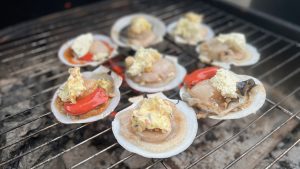 prepared scallops with toppings arranged in a circle on a grill