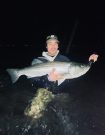 Ben Gowell in the water holding a large fish at night.