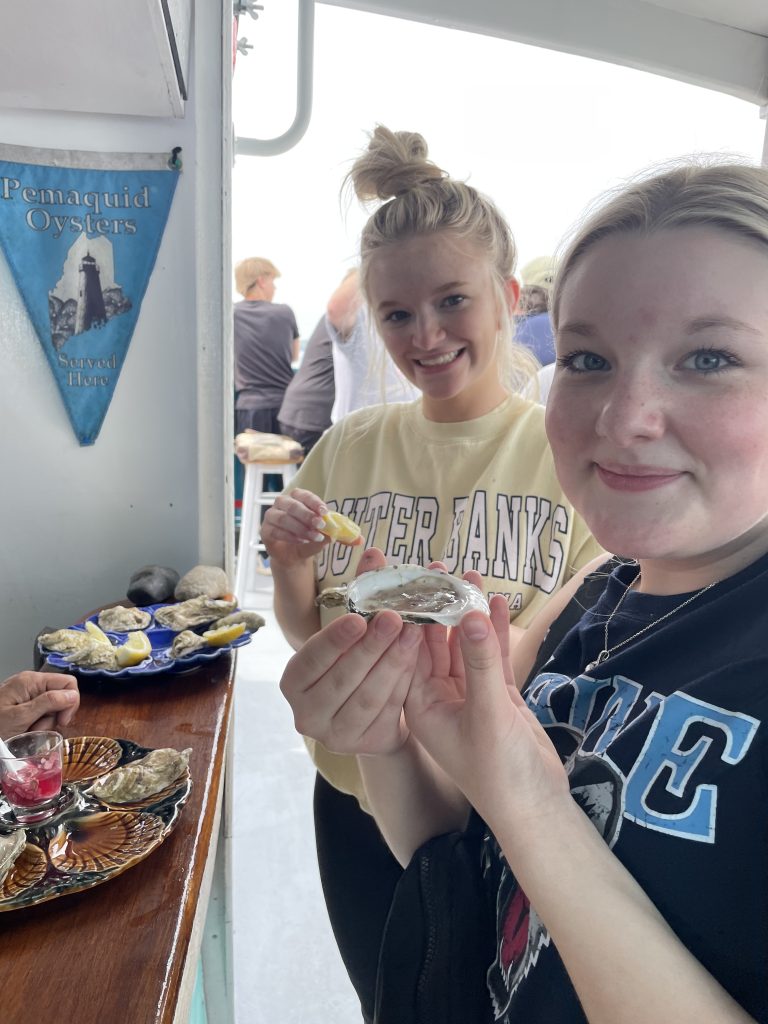 2 Students hold an oyster before eating it for the first time on a boat. 